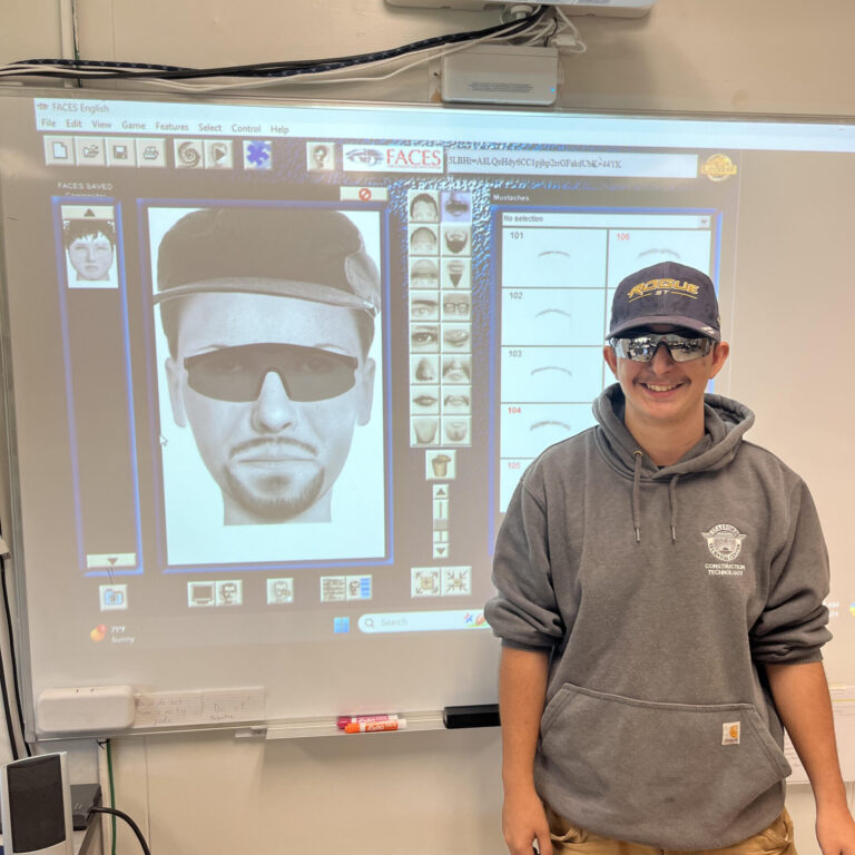 Student stand next to a projected image of a composite drawing meant to be him
