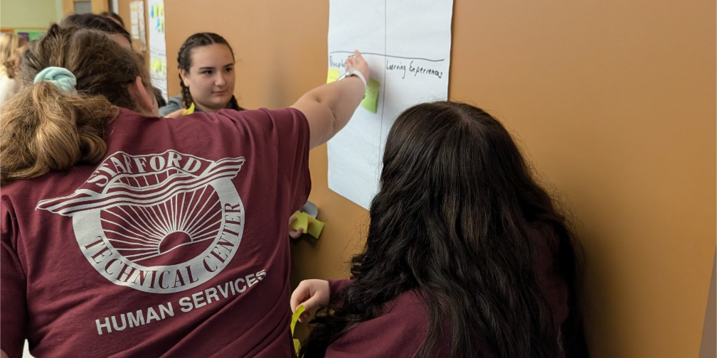 Students are writing on a paper taped to a wall