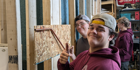Smiling student gives a thumbs up to show he is pleased with his angle offset of copper pipe.