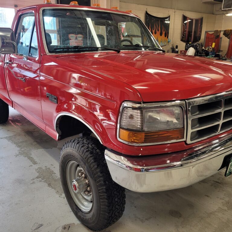 Red truck with fresh paint reflect the light from above.