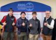 three students give thumbs up in front of a BROC sign with Director Tom Donahue