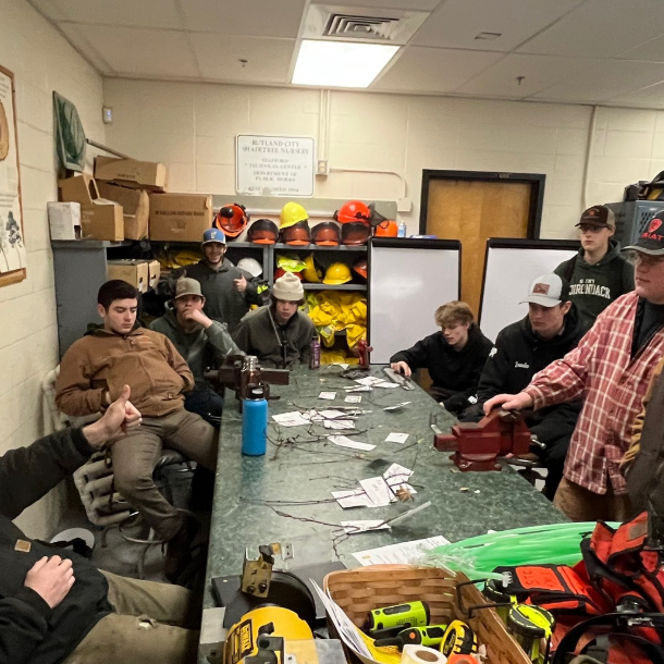 students sit around a table listening to Caleb speak