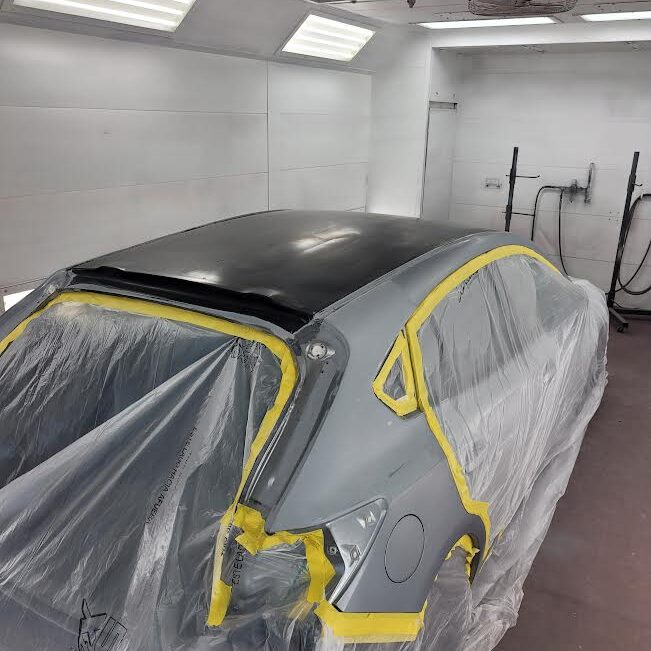 a car taped off and masked sitting in a paint booth