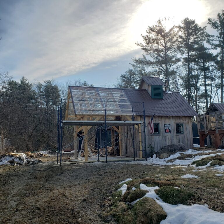 A picture of a sugar house with an extended roof. Staging is set up around the extended roof structure.