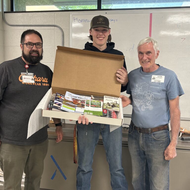 Luke stands with his prize package, flanked on one side by his instructor and the other side by Mr Clerihew