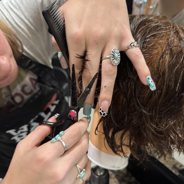 Student hands are using scissors to cut hair