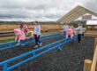 Children ride on pig shaped riding toys that slide on rails.