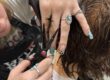close up of hands holing hair and a student using shears to trim the hair