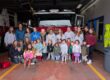 a group of preschoolers and high school students stand in front of a firetruck