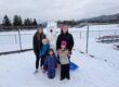 3 preschoolers gather around a snowman with two adults