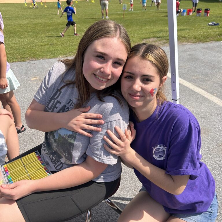 Two students are smiling as they pose for the camera